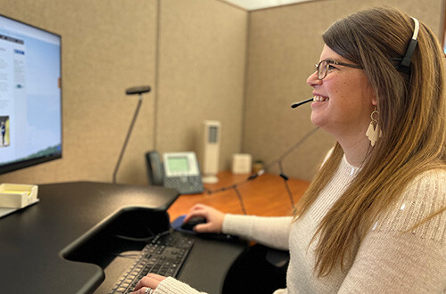 A claims associate works on the computer while taking a call.