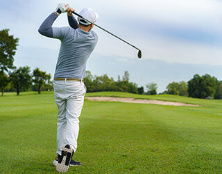 Man at the golf course swings the golf club.