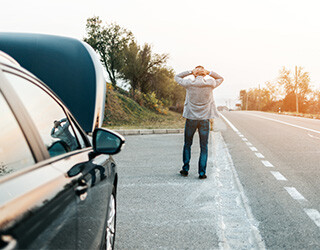 Man stands with hands on this head on side of road.